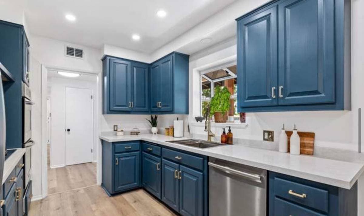 Luxury remodeled kitchen with blue cabinets and granite white countertops with stainless steel appliances